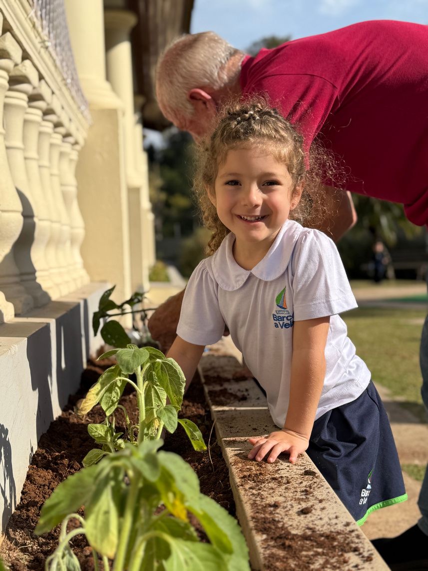 Menina sorridente cuidando das plantas da horta