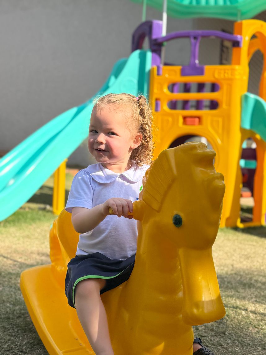 Criança pequena brincando no cavalinho do parque