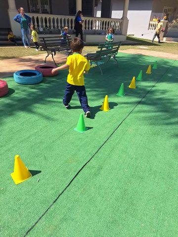 Criança percorrendo circuito com cones no pátio